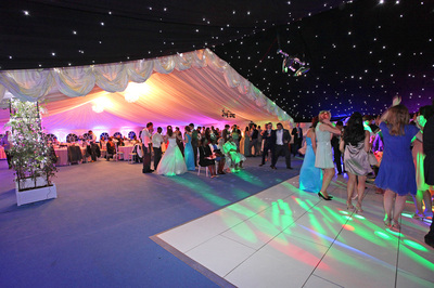 dorset wedding marquee LED uplights, crystal chandeliers, light blue carpet, white dance floor, mirror ball and reveal curtain
