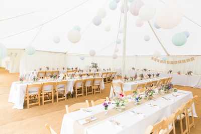 Dorset wedding traditional marquee with hanging lanterns, trestle tables with wooden folding chairs