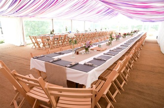 Dorset wedding marquee with wooden folding chairs and pink ribbon drapes