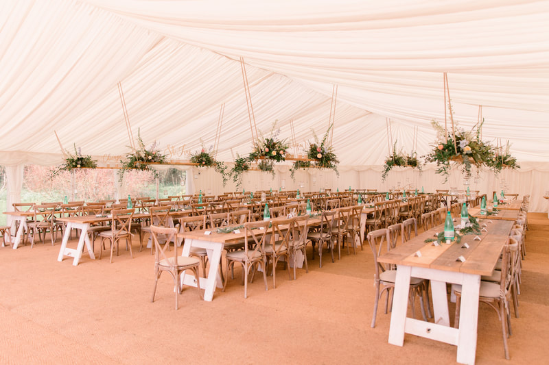 dorset wedding marquee with hanging planks, rustic tables and ivory linings